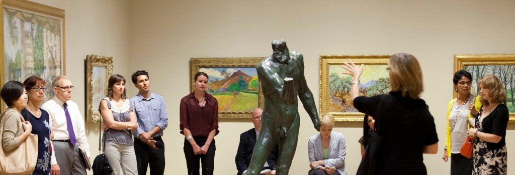 A group of people standing around a statue in a museum.