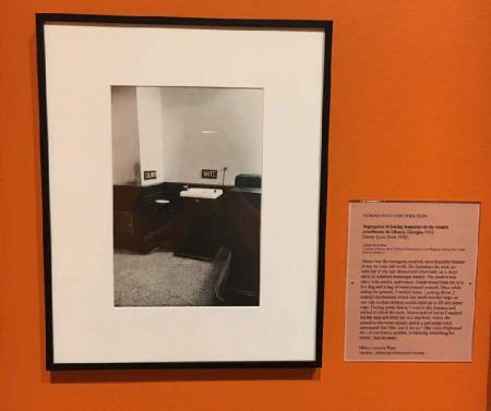 The winning label is seen next to a black-and-white photograph of drinking fountains, one labeled "white" and the other "colored."