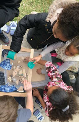 Looking down on children sifting sand and pottery at an archaeological site. 