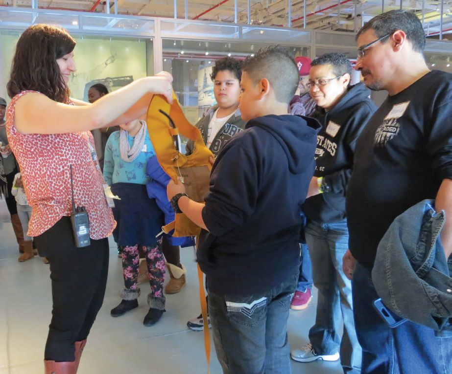 A tour group with a woman tour guide examine a deflated flotation device.