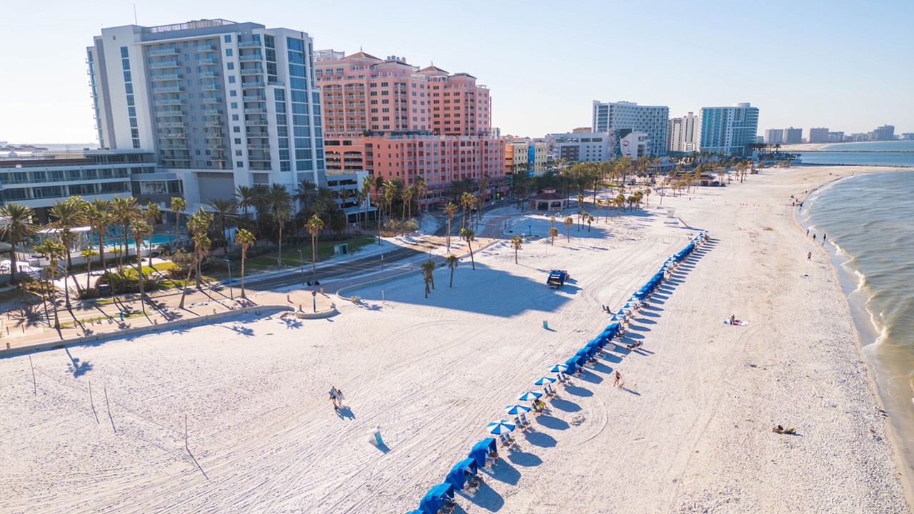 An aerial view of a beach coastline abutting multi-story buildings
