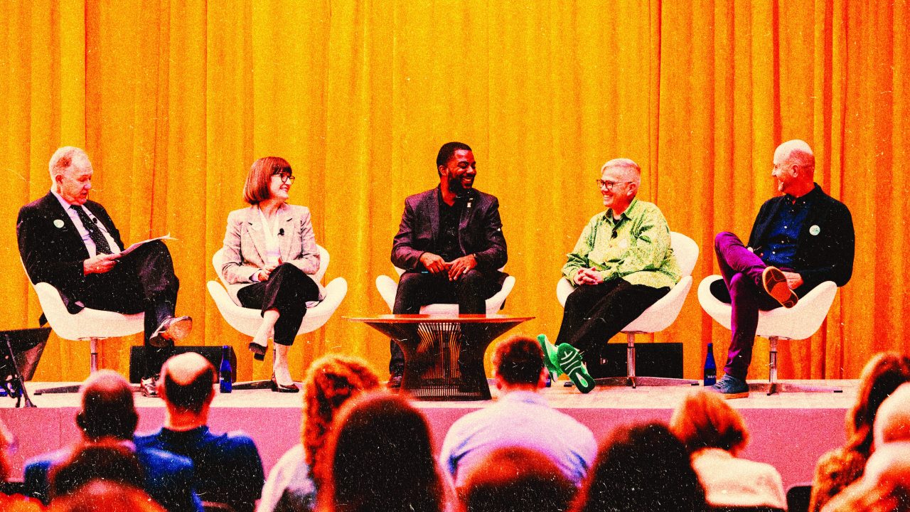 A group of people seated on a raised stage in front of an audience