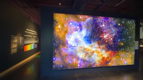 Interior of visitor center with a multi-colored view of a galaxy on a dark colored wall.