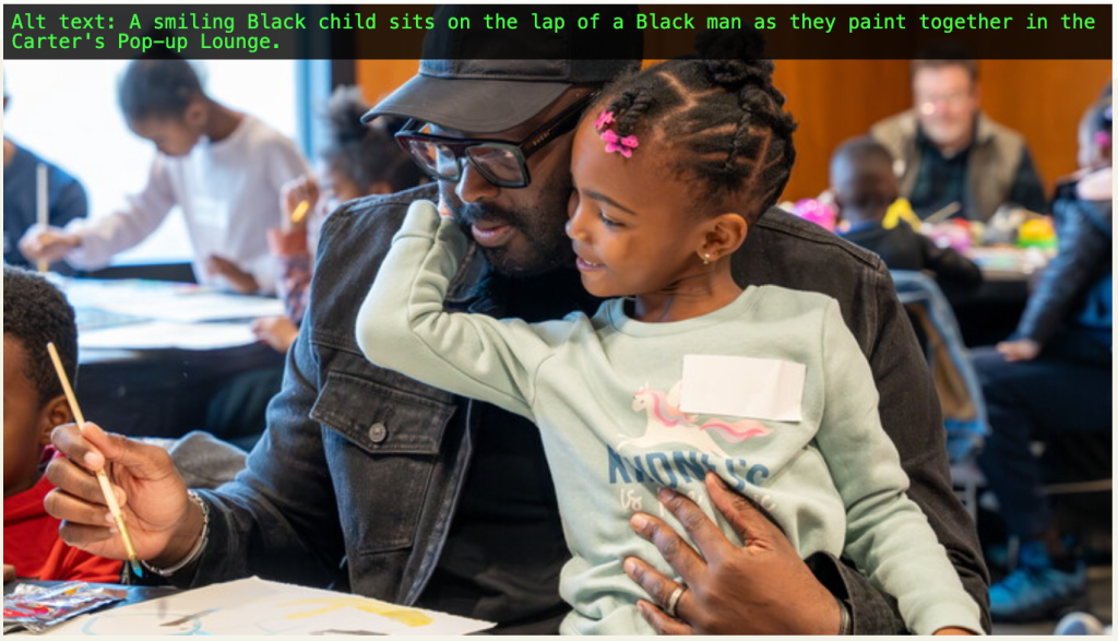 A smiling Black child sits on the lap of a Black man as they paint together in the Carter's Pop-up Lounge.