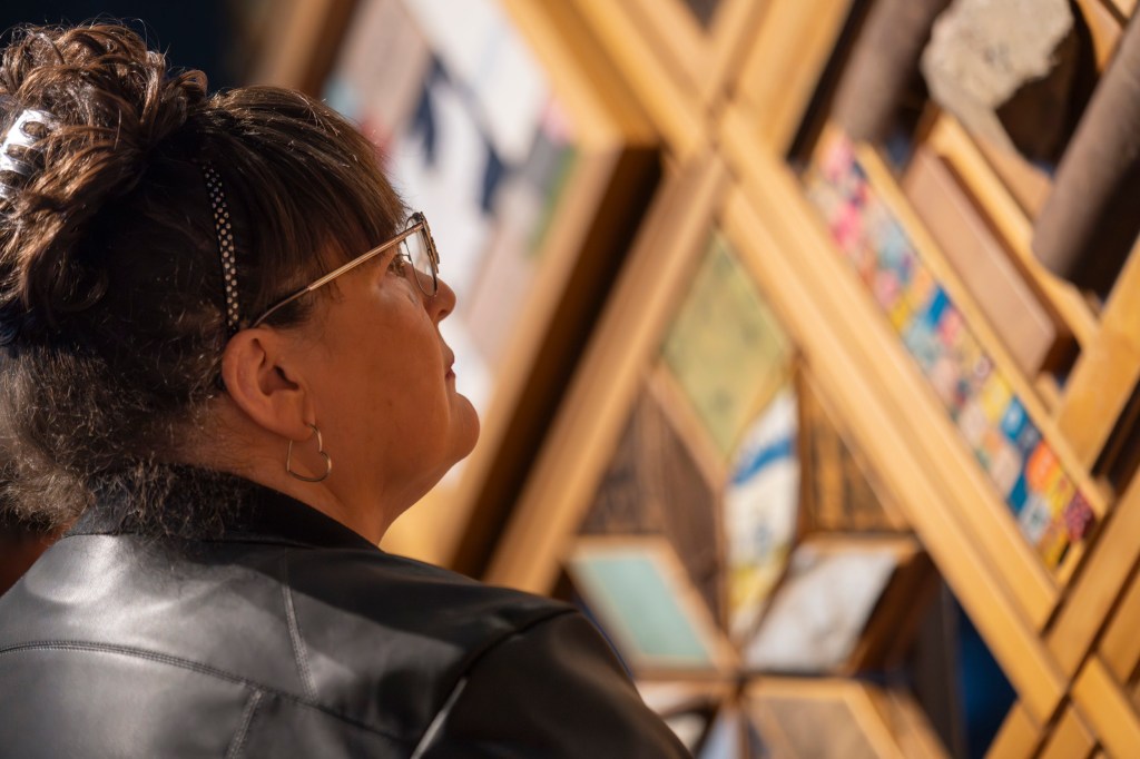 A person looks at an exhibit's patchwork, close up.