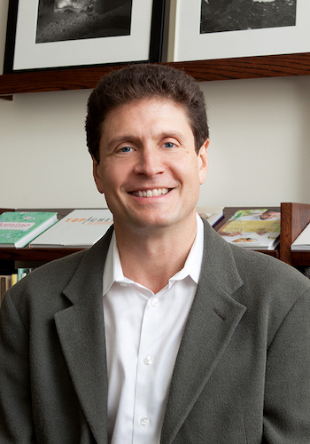 Photo of Charles Melcher. He is smiling with brown hair in front of a bookshelf.