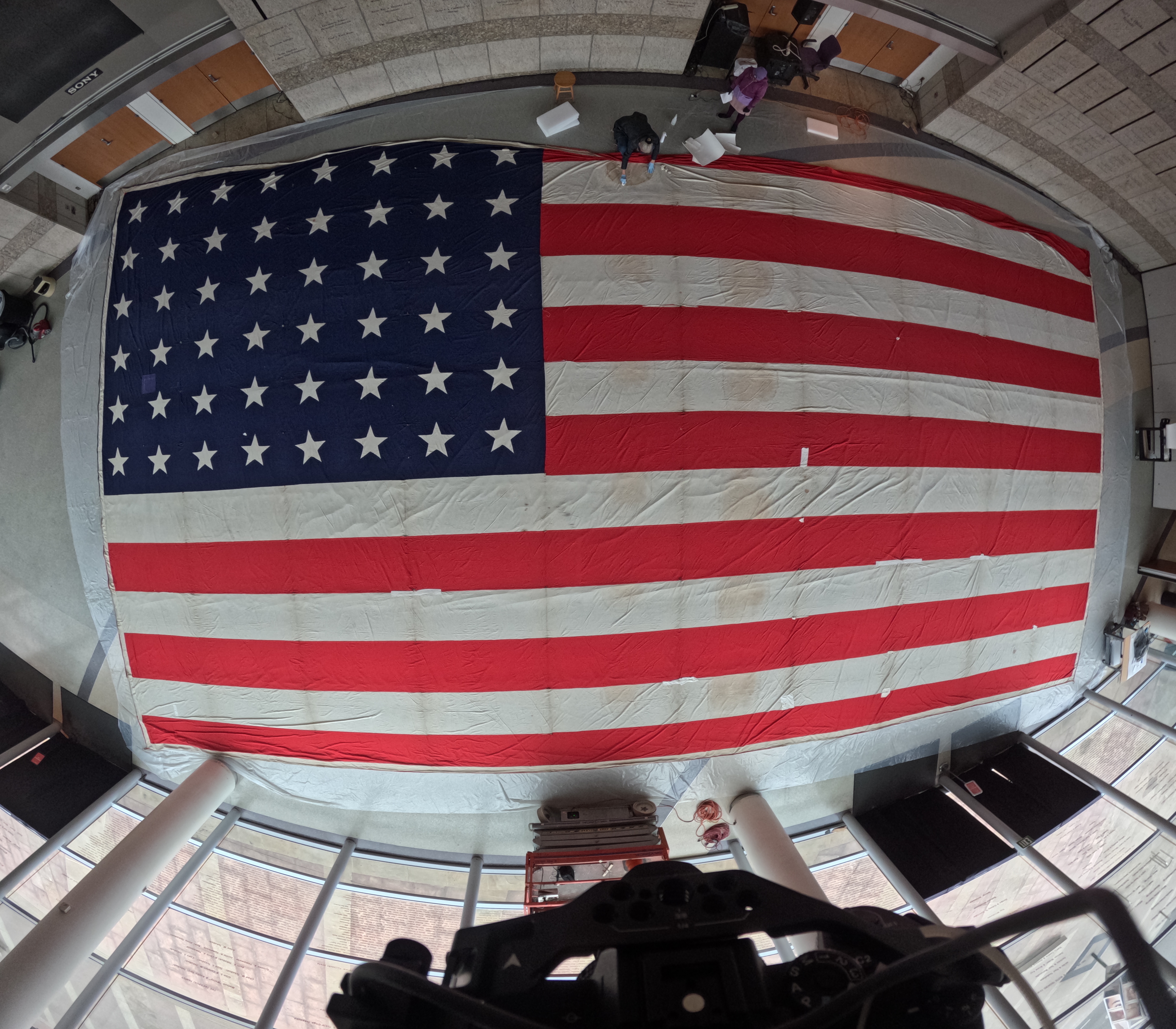 A view from above of a giant American flag being worked on by Collections staff.