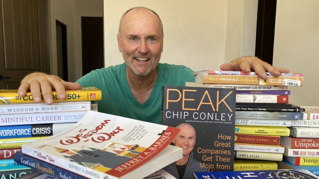 A person sitting down behind a pile of books