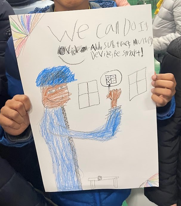A student drawing reading "We can do it, add, subtract, multiply, devide, be smart!" with an illustration of a teacher