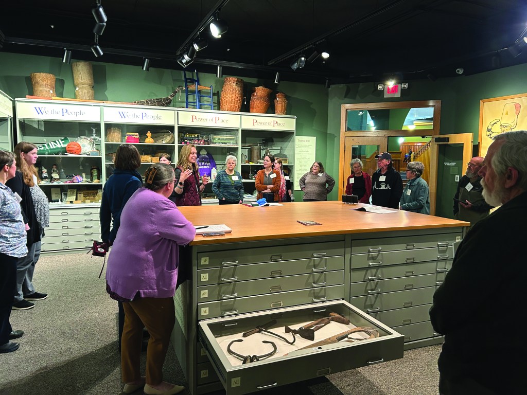 Participants of a workshop in a collections room with many shelves and drawers of storage.