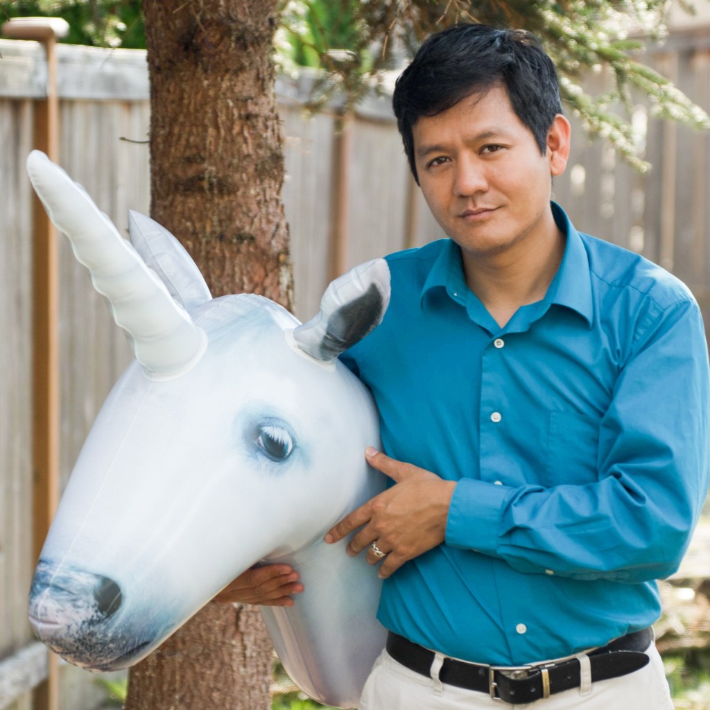 Headshot of Vu Le holding an inflatable unicorn