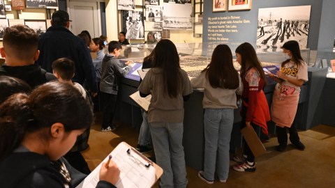 A group of fourth graders in one of the Japanese American National Museum's galleries. The students have clipboards and are writing about what they see.