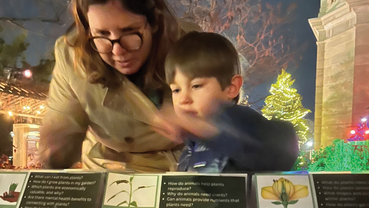 An adult and child standing over a plaque with lists of questions