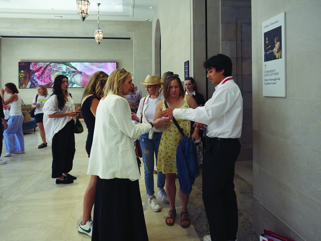 A staff member from The Frick Collection helps visitors in their Reception Hall.
