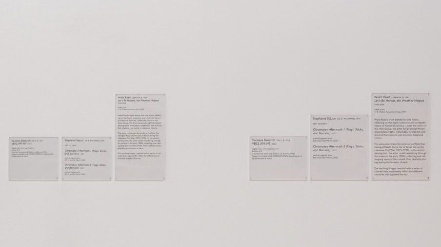 Two groupings of three wall labels with black text on a white background are hung on a white wall. The labels are all of slightly different size, with different font size, leading, and other typographic treatments. Overall, the group to the right is larger in size and font-size than the group on the left.

