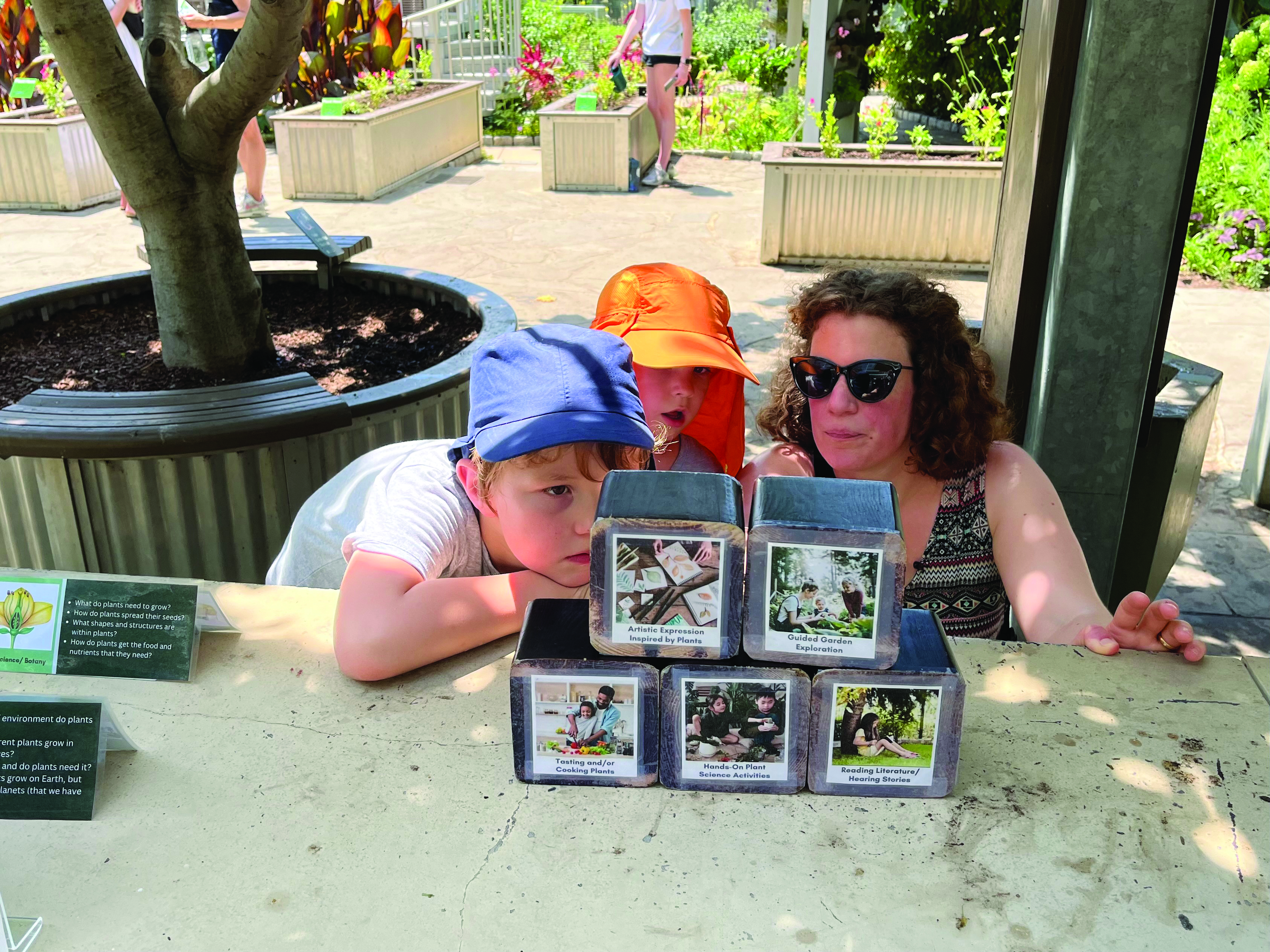 Two children and an adult looking at a stack of cubes with labels on them