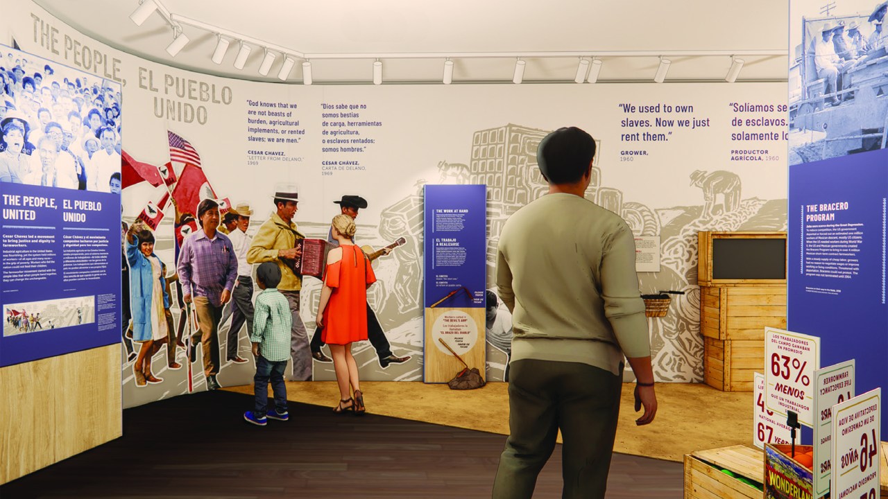 A design rendering shows the graphic program for the César E. Chávez National Monument. A sepia-toned graphic mural of farmworkers in a field wraps around the back of the gallery space from floor to ceiling. Color photographic images of people marching and holding flags overlay the mural. Blue and white didactic panels, some with photographs on top, also fill the space. Three figures, two adults and one child, give a sense of the scale of the gallery.