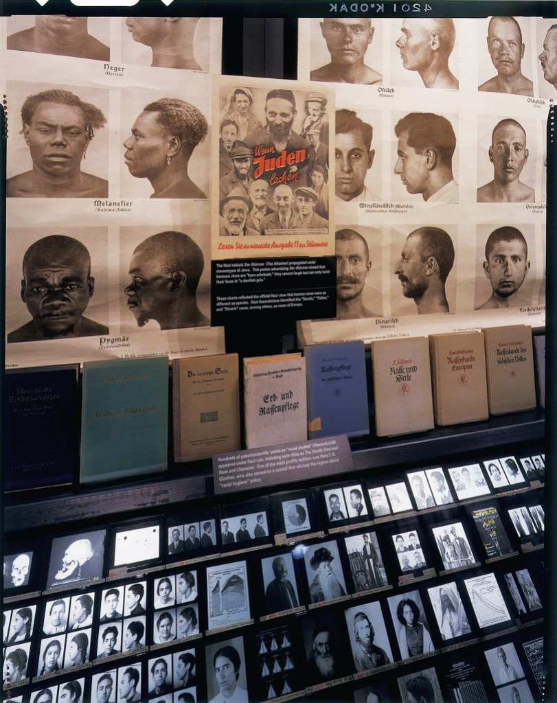 Expanded version of the header image. Books and photos of people in a glass exhibit case.