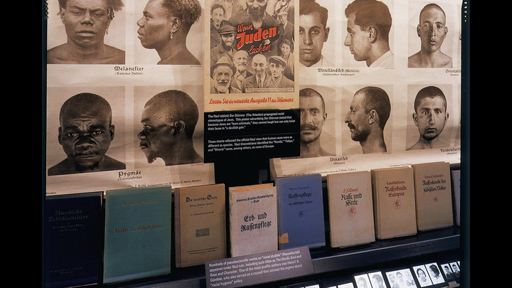 Books and photos of men in a glass exhibit case