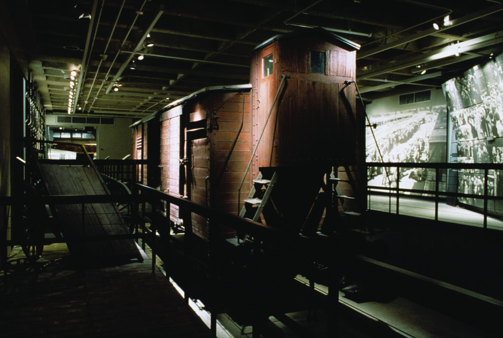 Dark gallery with a historic rail car on display.