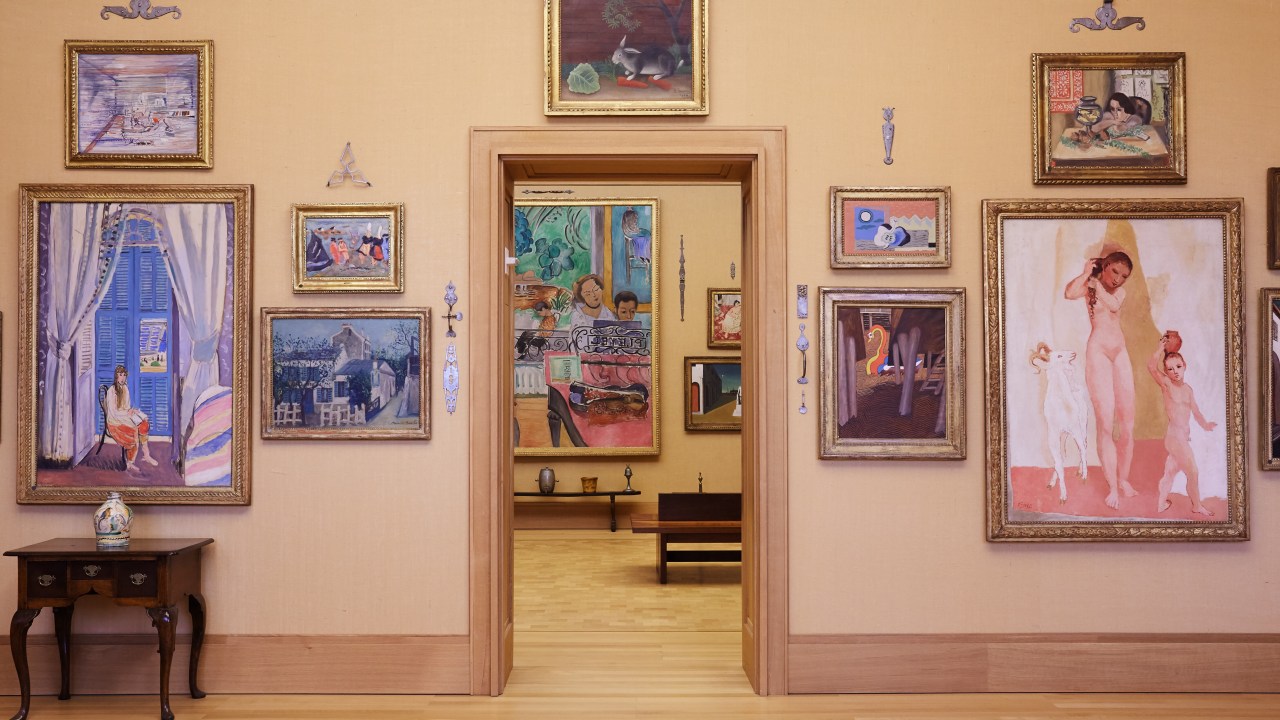 View through a doorway in a museum gallery with paintings displayed on the walls