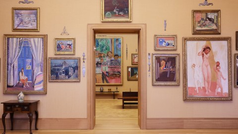 View through a doorway in a museum gallery with paintings displayed on the walls