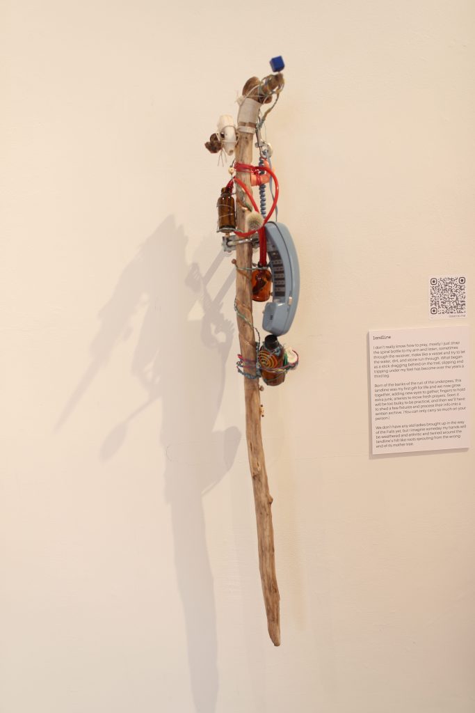 A walking stick with a phone and other items wrapping around it.