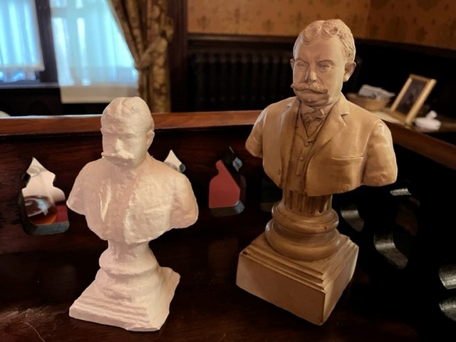A bust of a historical figure next to a smaller recreation without finish