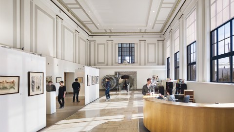 Big space with white walls with art on them and a reception desk in the front.