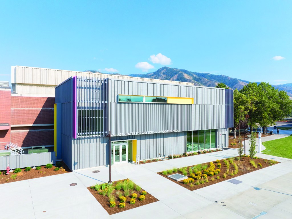 Wanlass center for art education and research is a modern looking building against a mountain backdrop.