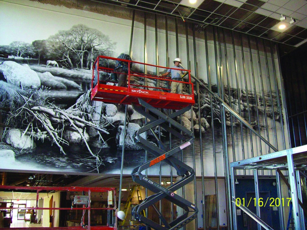 Construction workers building a frame in front of a mural to protect it from damage.