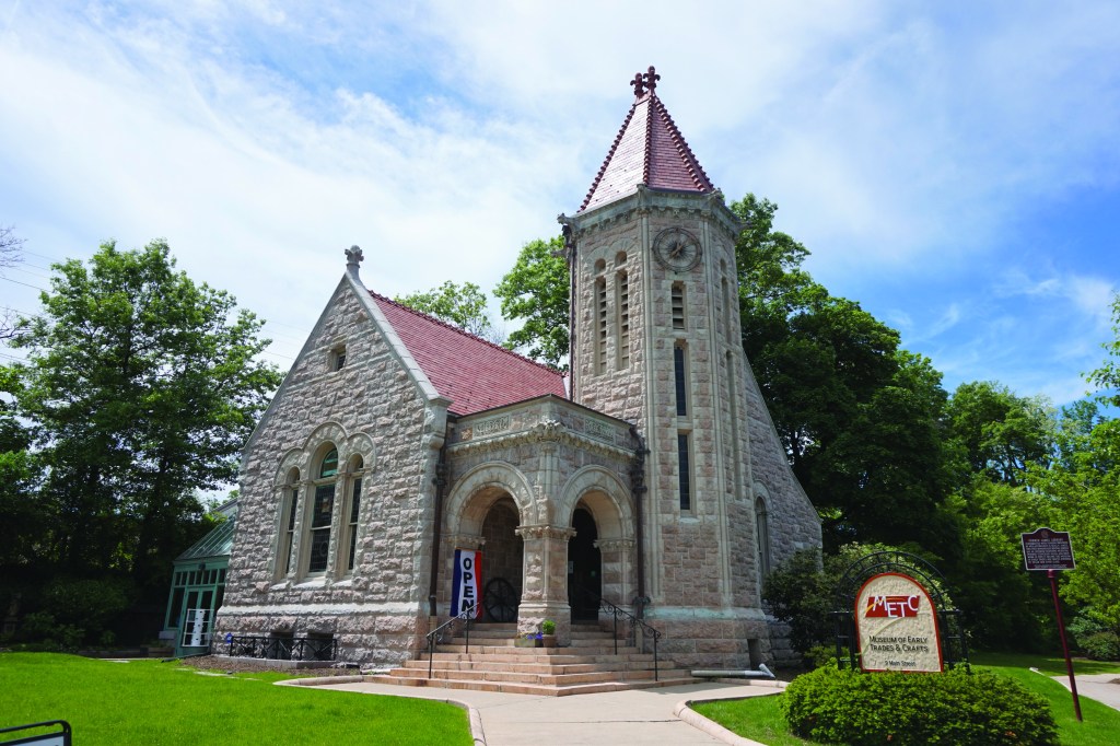 Stone building in front of green trees.