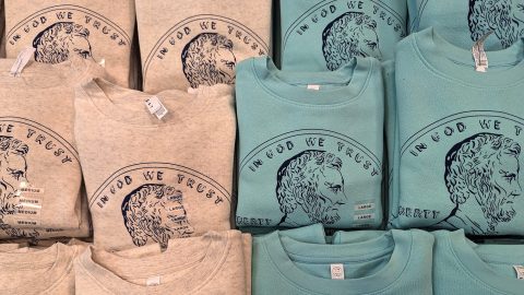 Stacks of folded t-shirts with illustrations of the penny with Abraham Lincoln's face on it