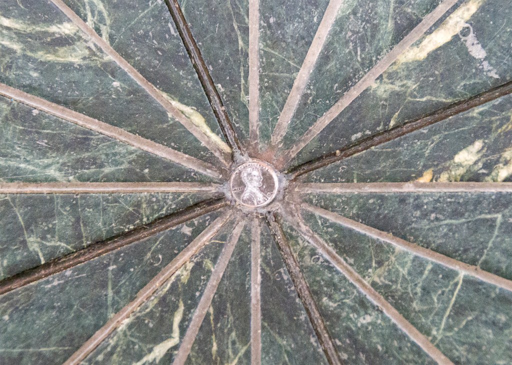 Triangular floor tiles converging on an embedded penny
