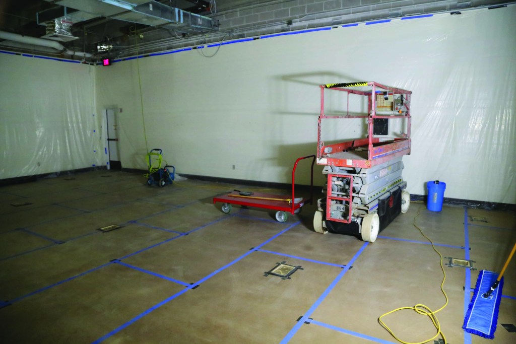 Room under construction with blue tape running along the top of the walls and on the floor.