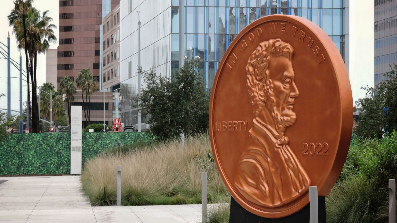 A statue of an oversized penny in front of a building