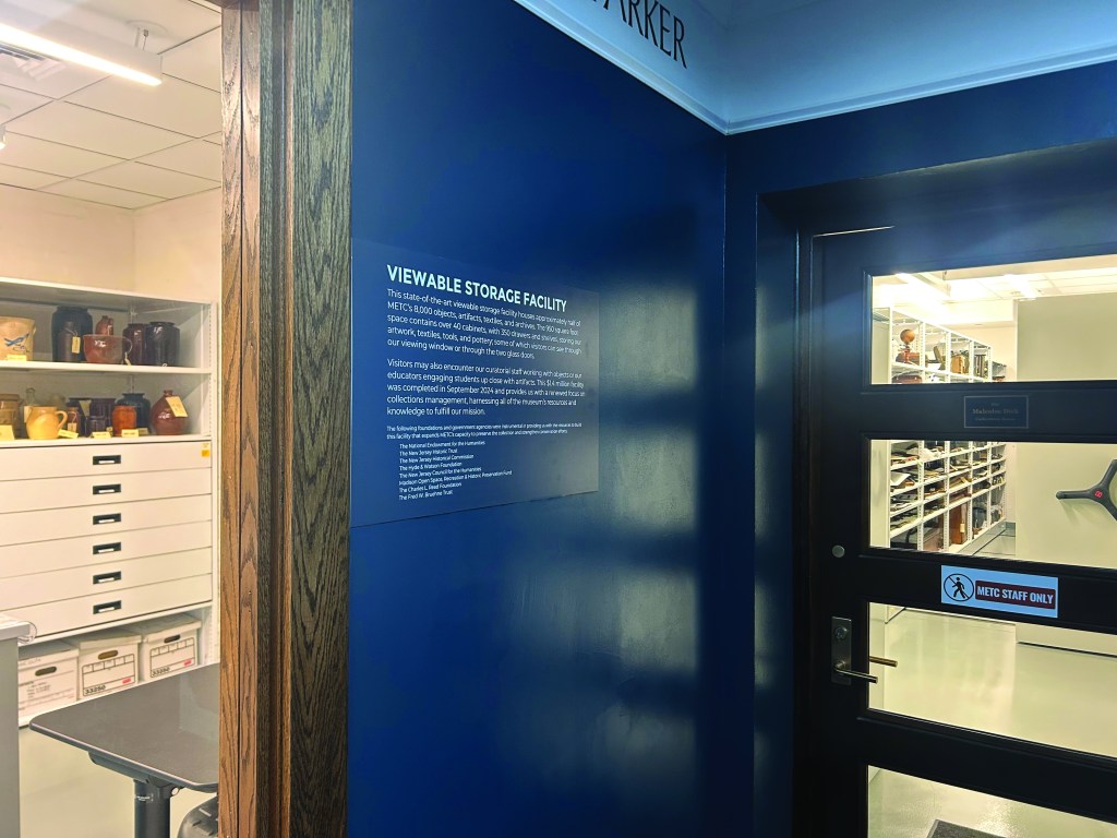 Window into museum storage facility with label on blue wall.
