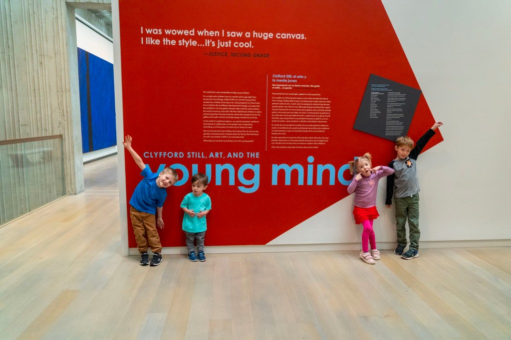 Four children making silly faces and poses outside a gallery.