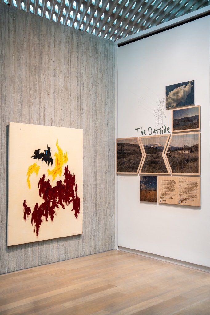 A large artwork and photographs in a gallery. The photographs have a label "The Outside".