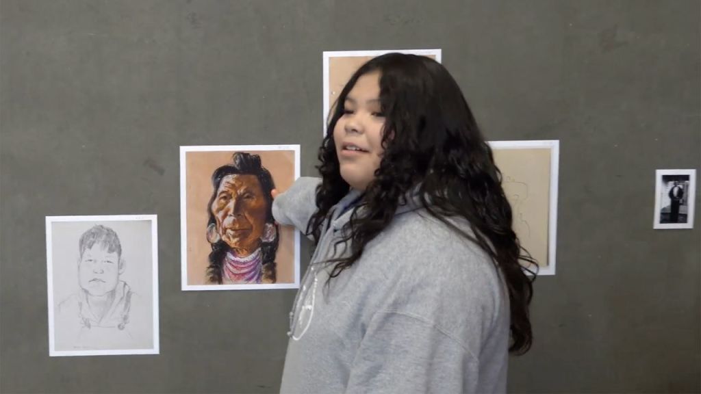 A girl points to a printed image of an artwork.