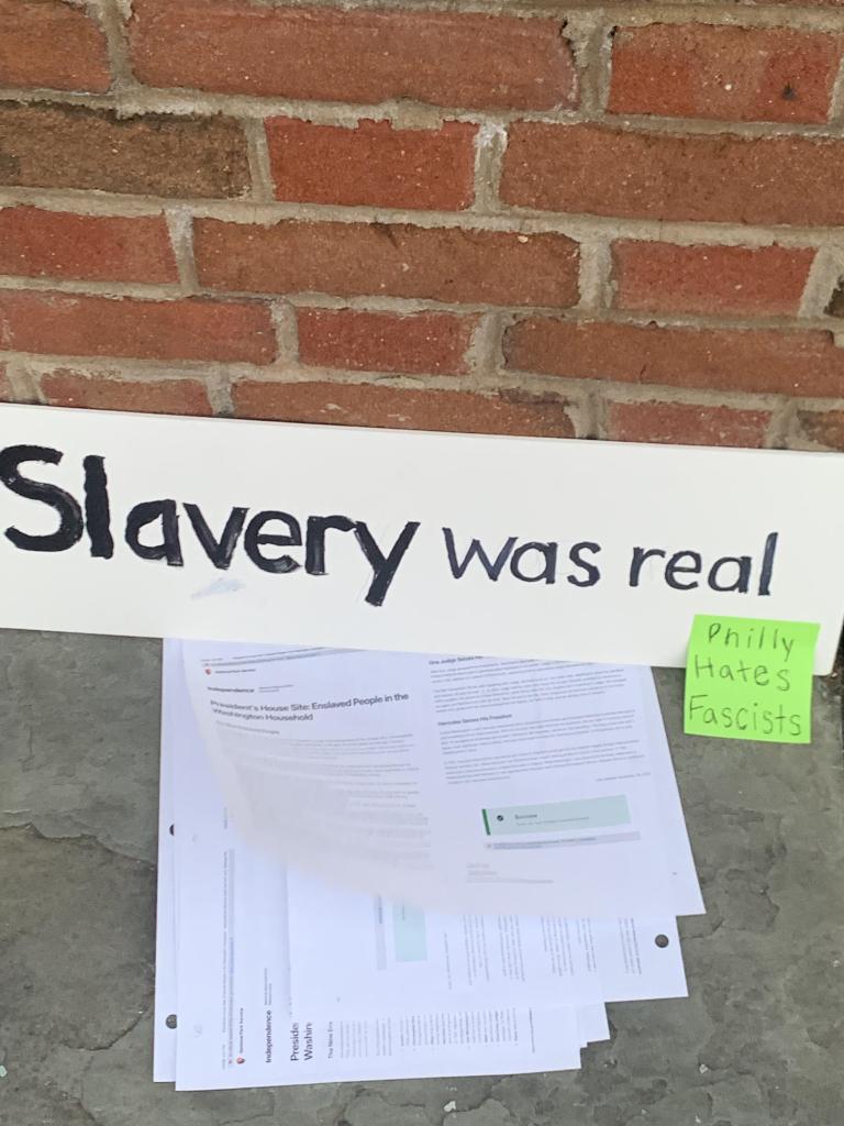 Sign reading "slavery was real" with a post-it reading "Philly hates fascists".