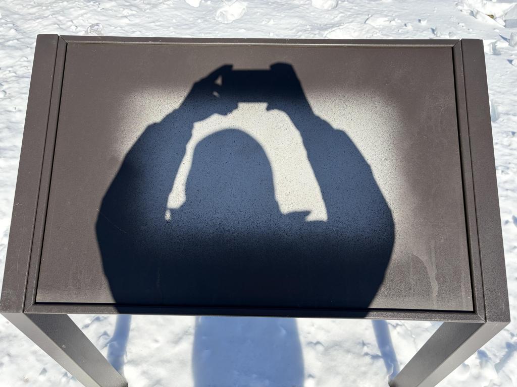 A shadow of the person taking the photo on a display where the sign has been removed.