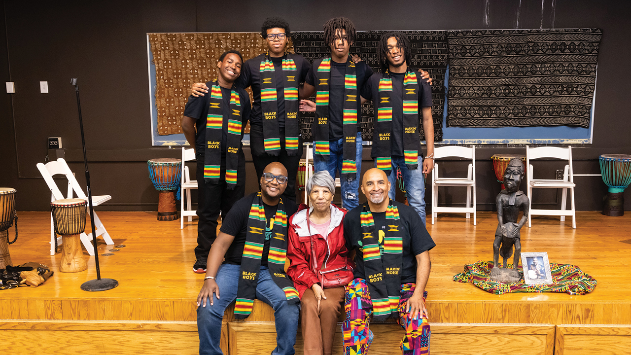 Group of African American men posing with an African Ameircan woman dressed in red
