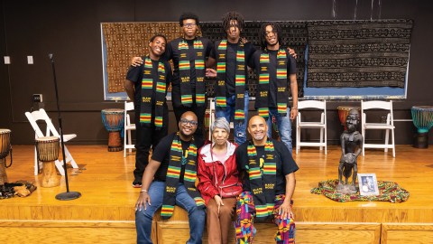 Group of African American men posing with an African Ameircan woman dressed in red