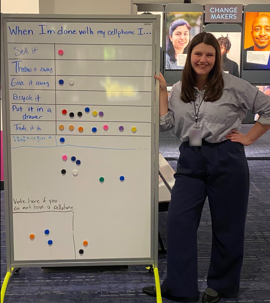 A female college student wearing professional attire stands next to a large whiteboard with the statement, “When I’m done with my cellphone, I . . .” written on it. 