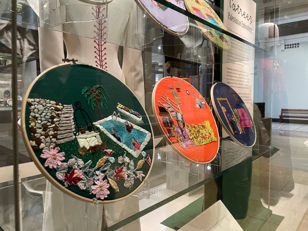 Three works of embroidery, displayed on mounts made of clear acrylic.