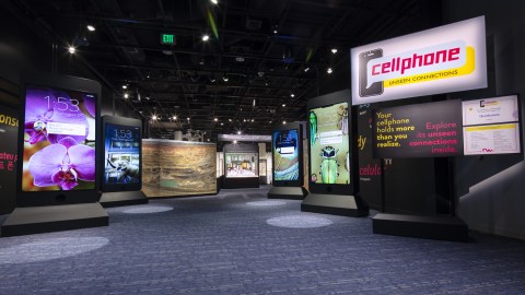 Four 10-foot-tall screens made to look like giant smartphones in a museum gallery.