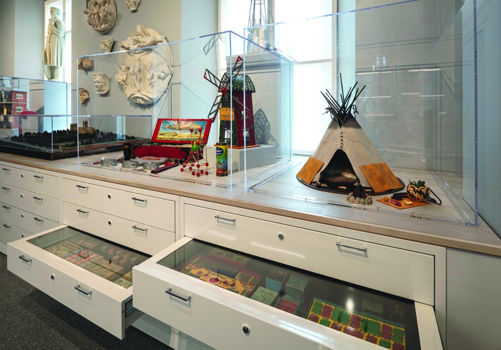 Cabinetry with open drawers showing toy collection in a museum.
