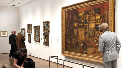 Visitors viewing paintings on a white gallery wall in the Harvard Art Museum.