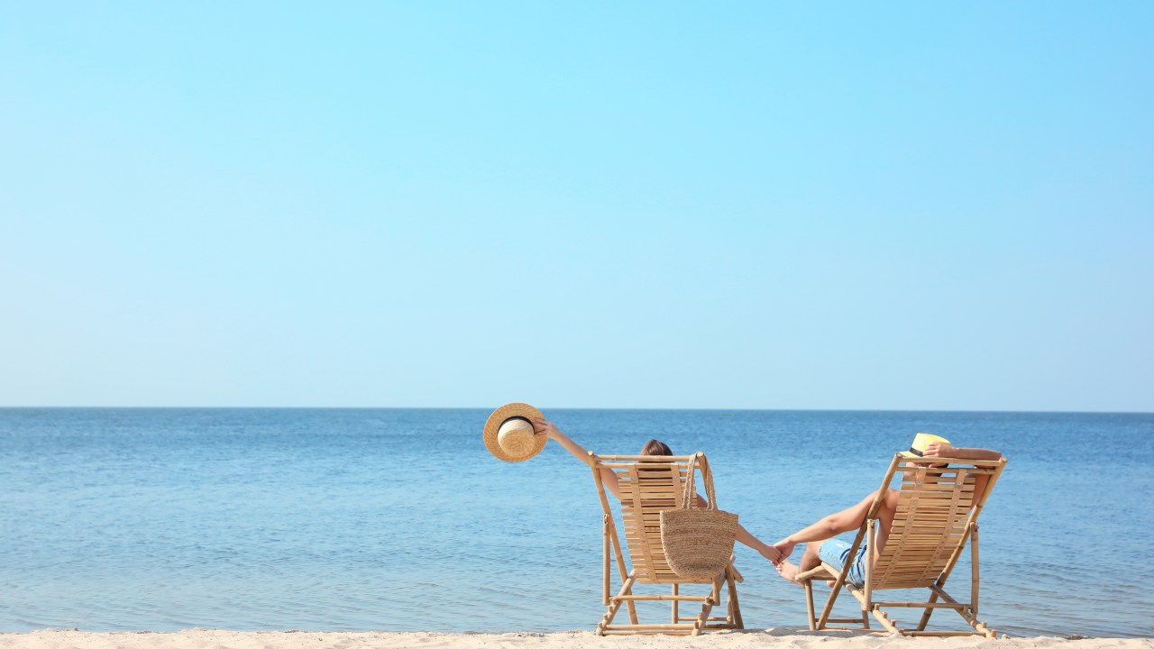 Young couple relaxing in deck chairs on beach